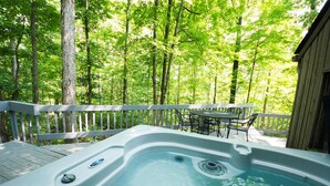 Un bain à remous sur une terrasse en bois, entouré d’arbres.