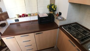 A kitchen with a wooden countertop, a gas stove, and a microwave. There is a potted plant on the countertop. - Porta Camollia Apartment (Siena)