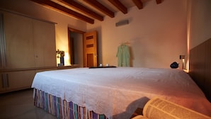 A bedroom with a large bed, a wardrobe, a mirror, and a hanging robe.