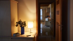 A hallway with a lamp, a vase with flowers, and a remote control on a table.
