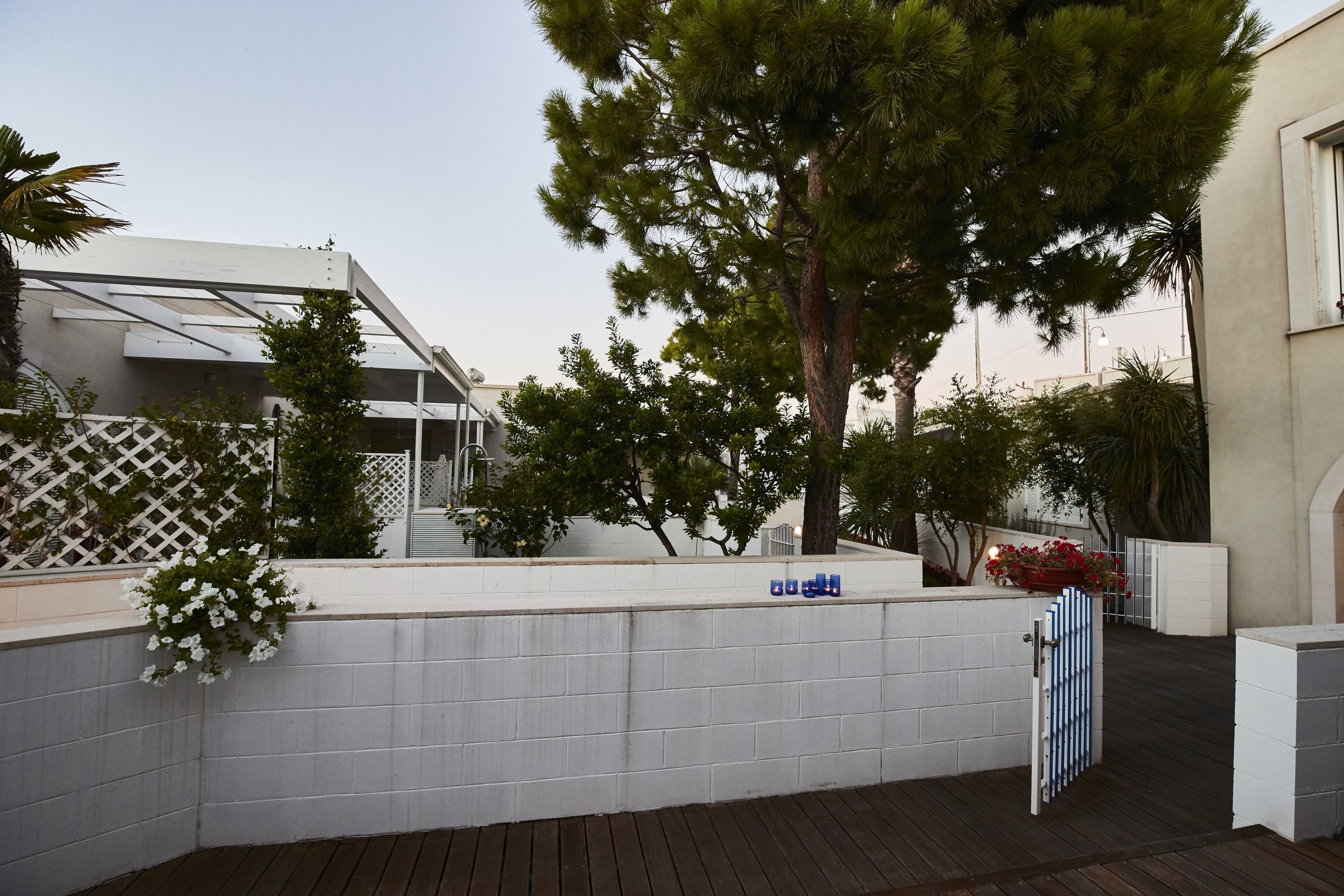 A modern outdoor area with a wooden deck, white walls, and a metal gate.