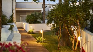 A pathway leading to a building with a white exterior and a wooden deck.