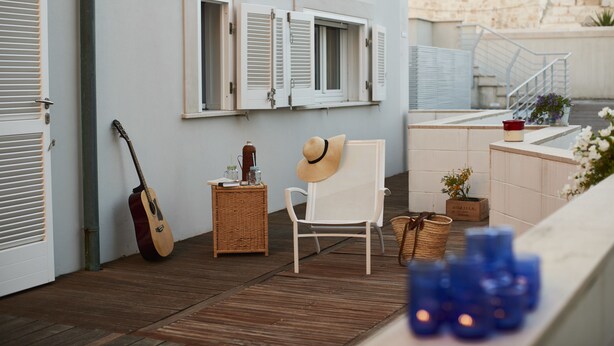 A room with a wooden floor, a white chair, a guitar, and a wicker basket.