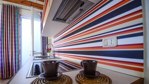 A kitchen with striped wall decor, a sink, and two cups on coasters. - Residence Cala Paura - Vecchio Frack (Polignano a Mare)