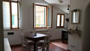 Un coin repas avec une table et des chaises, une cuisine équipée d’un four et une fenêtre avec des rideaux.