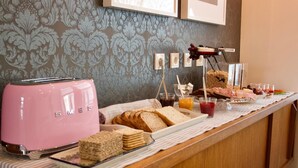 A breakfast buffet with a pink toaster, bread, pastries, and juice. - Akkeri Guesthouse (Stykkisholmur)