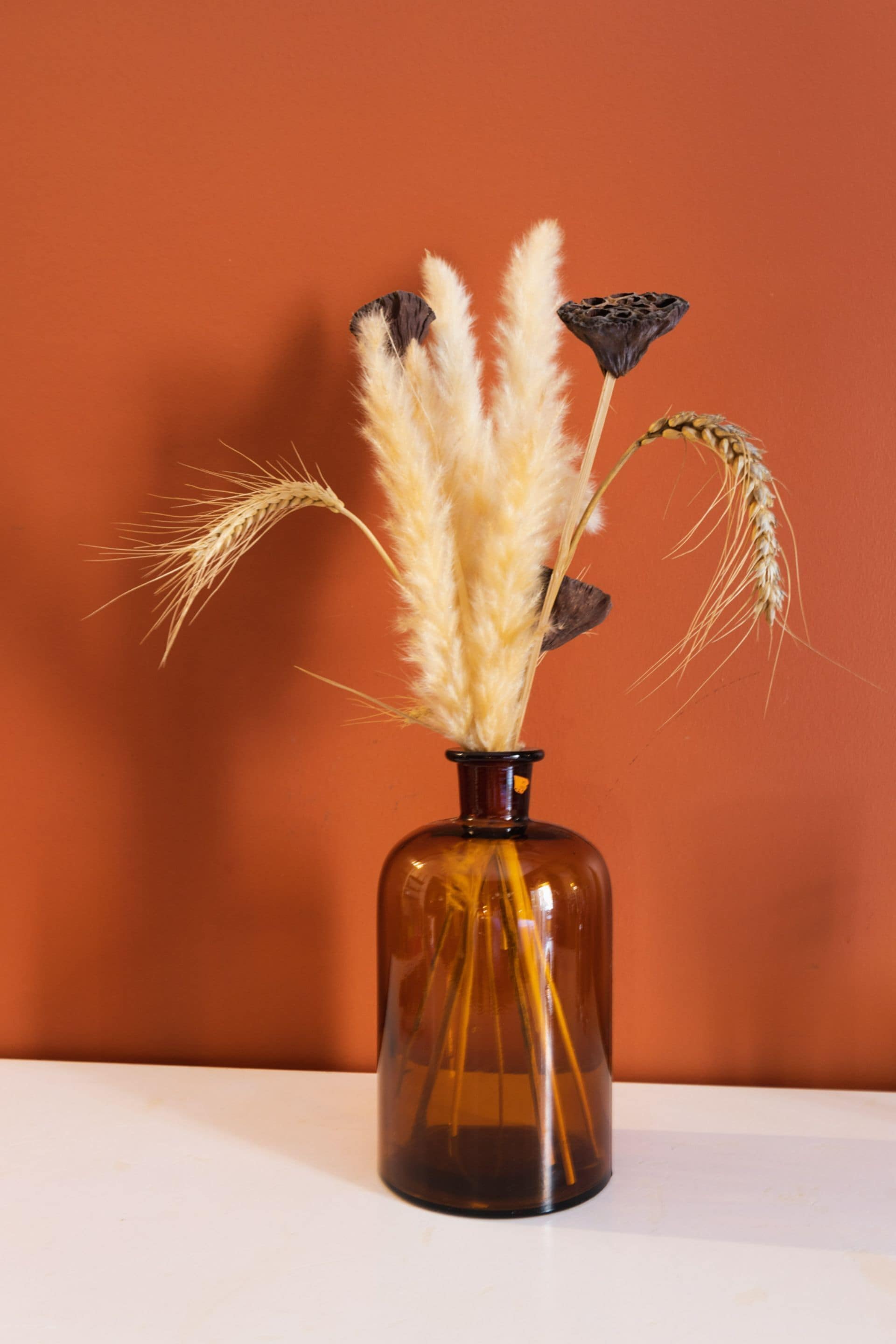 A vase with dried plants against a plain background.