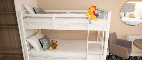 A bunk bed with a teddy bear and a gift bag on the top bunk.