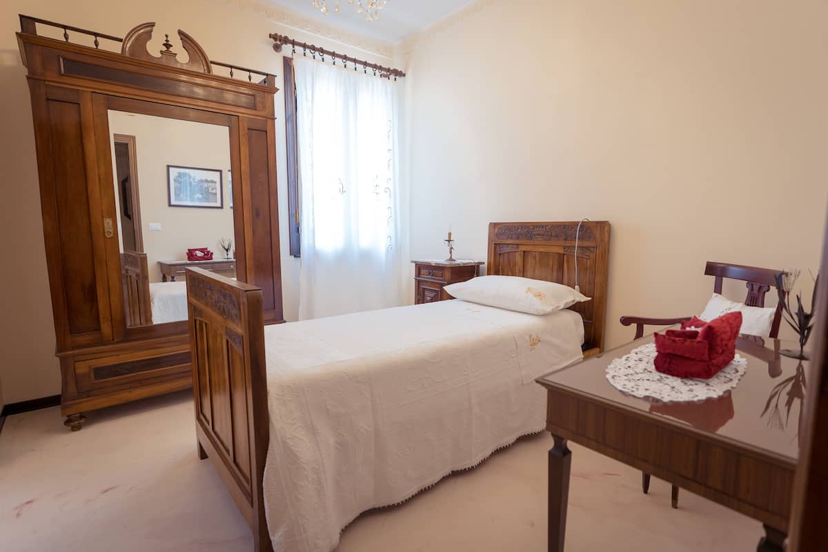 A bedroom with a wooden bed, a nightstand, a dresser, and a mirror.