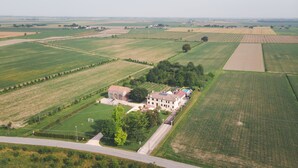 Vista aérea de una extensa propiedad con campos amplios, un edificio principal y una cancha de tenis.