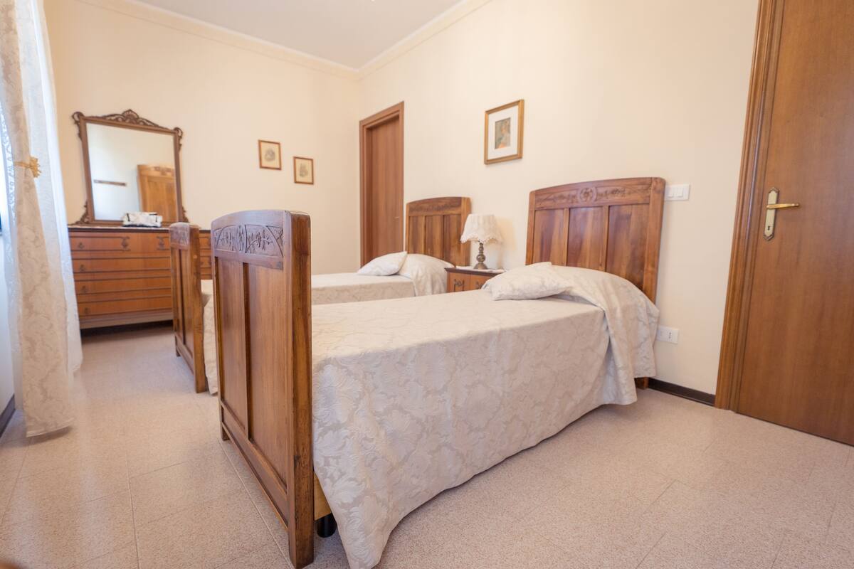 A bedroom with two wooden beds, a wooden dresser, a mirror, and a door.