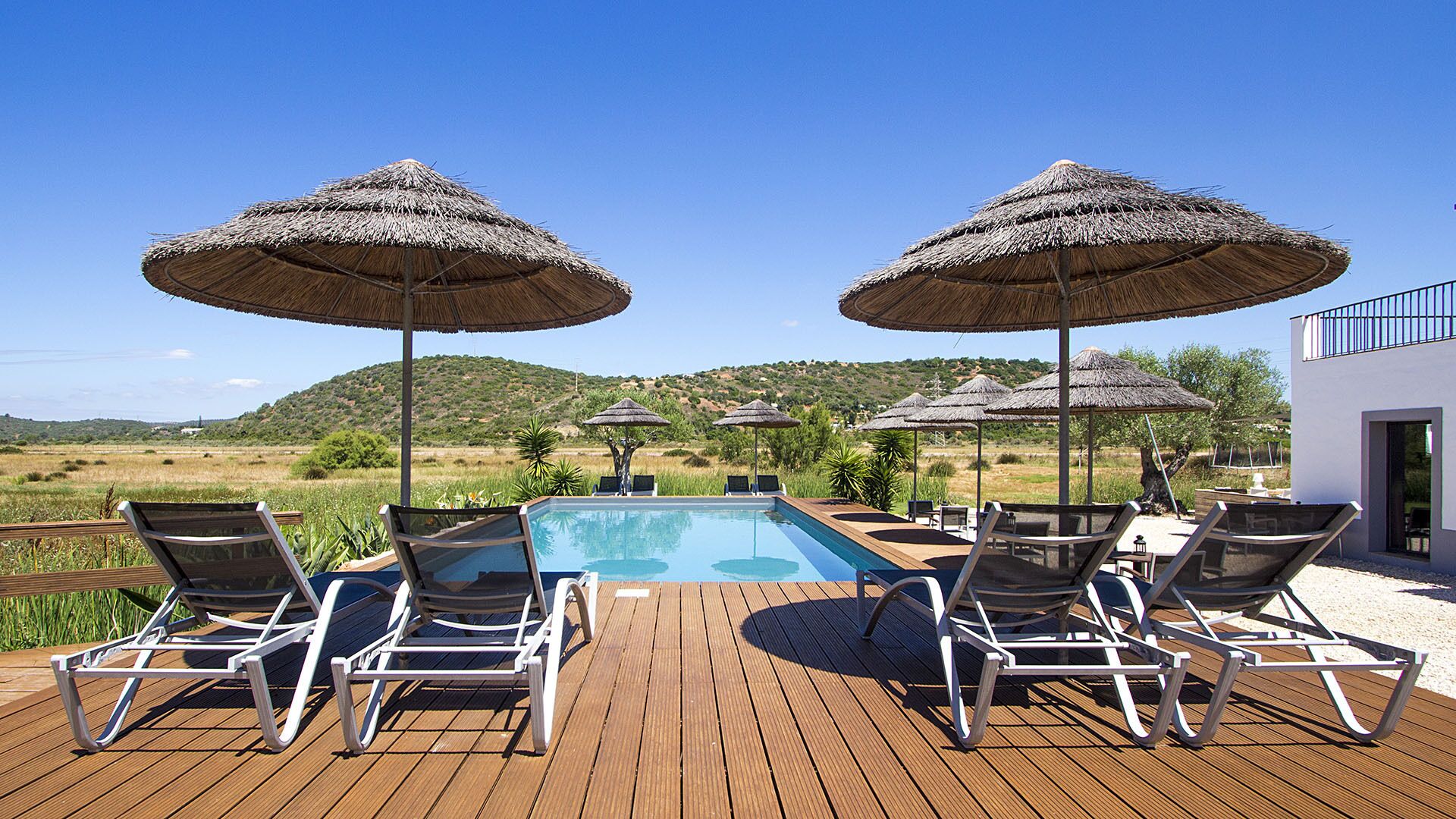 Una piscina al aire libre, sombrillas, tumbonas