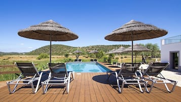 Una piscina al aire libre, sombrillas, tumbonas