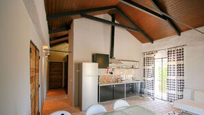 A modern kitchen with a dining area, featuring a glass table, white chairs, and a white sofa. - Tapada do Gramacho (Lagoa)