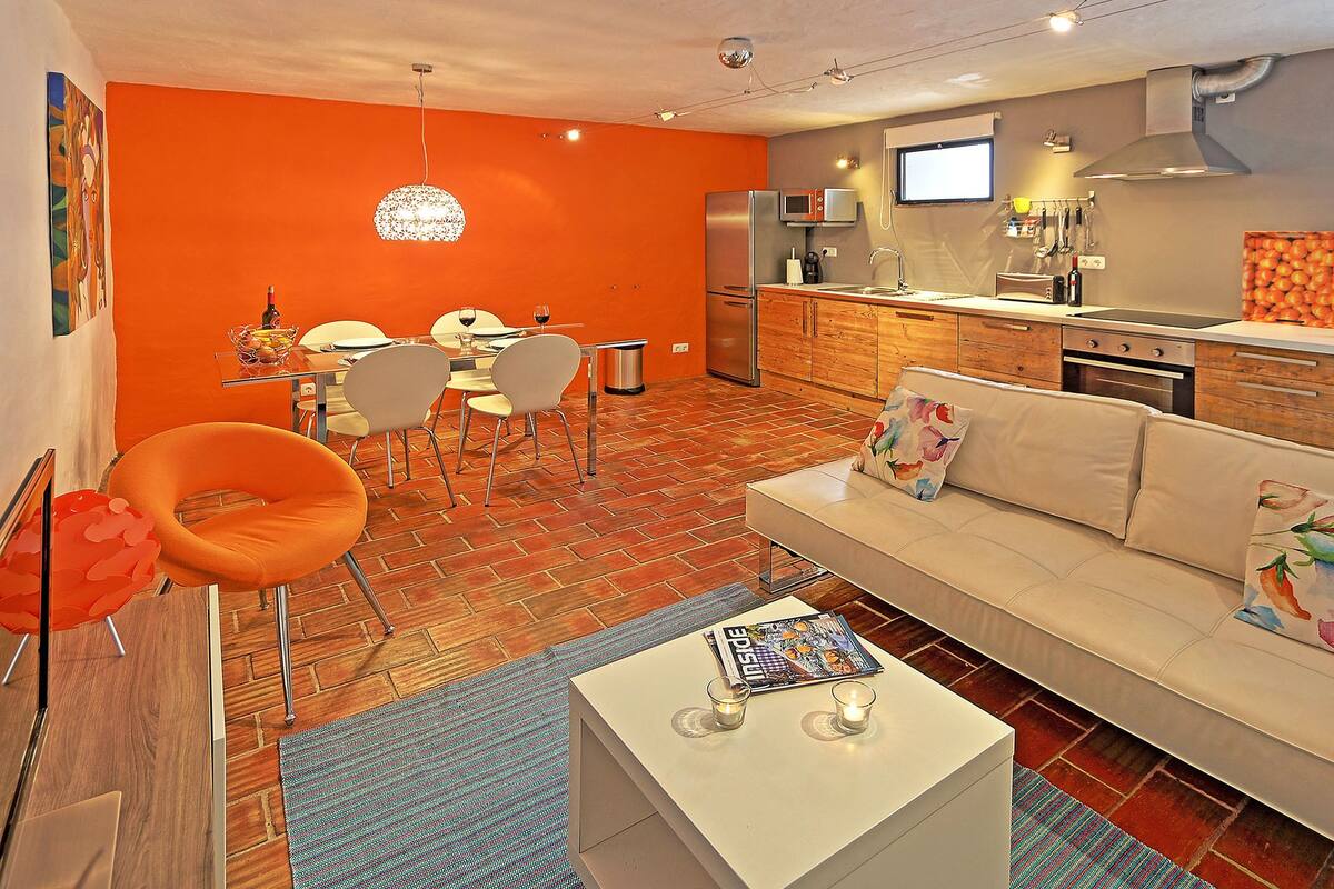 Una cocina moderna con refrigerador, microondas y estufa. Cuenta con un comedor con mesa y sillas.