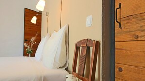 A neatly made bed with white linens, a bedside table with a lamp, and a wooden headboard. - Tapada do Gramacho (Lagoa)