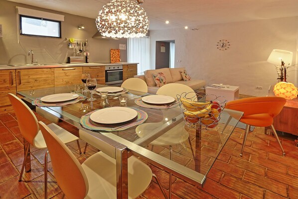 Un comedor moderno con una mesa de vidrio, sillas blancas y una lámpara colgante en el centro.