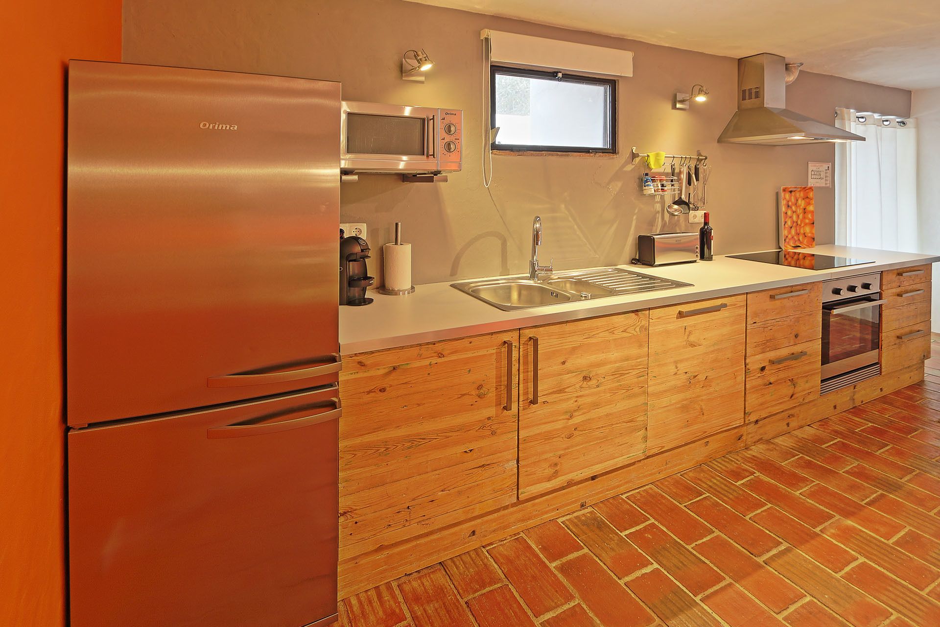 A kitchen with a stainless steel refrigerator, a built-in oven, a sink, and wooden cabinetry.