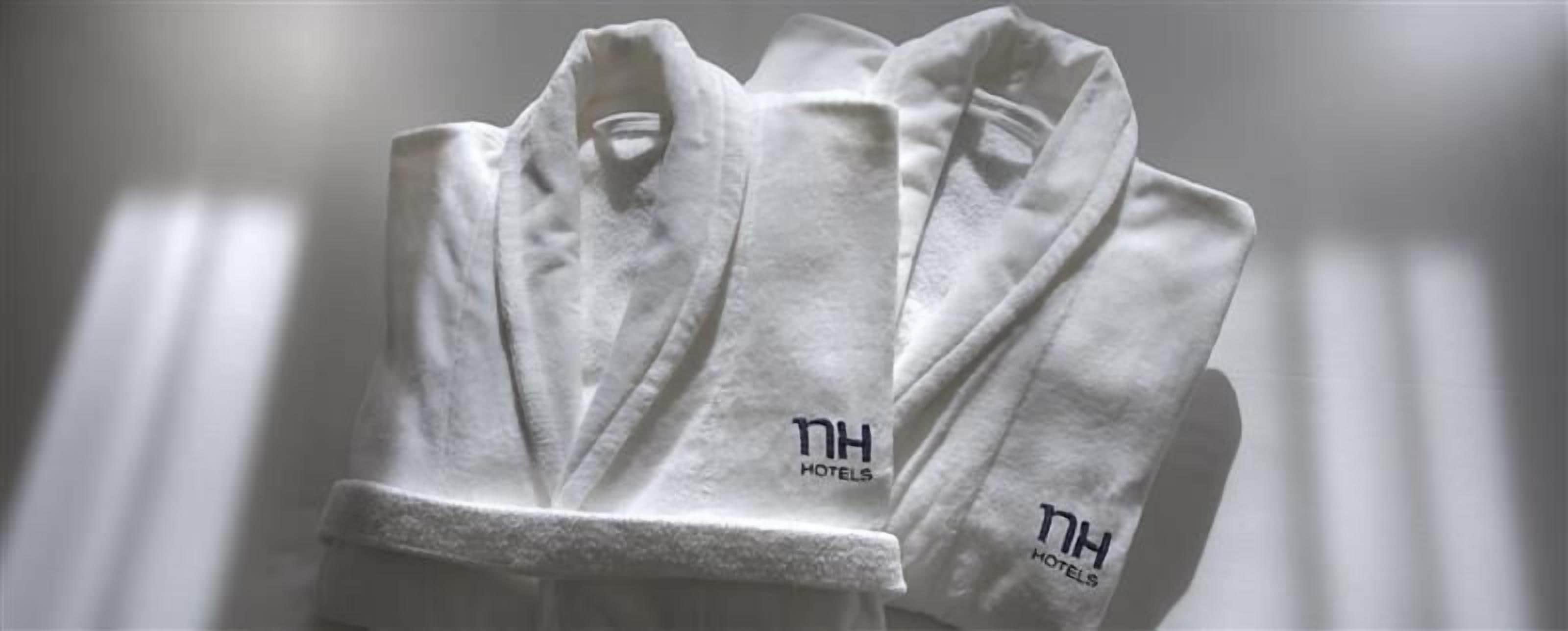A set of white towels with the logo "NH Hotels" on them.