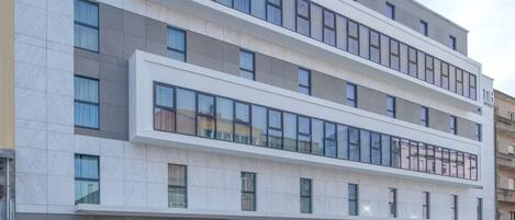 A modern hotel building with a flat facade, large windows, and a ground-level entrance.