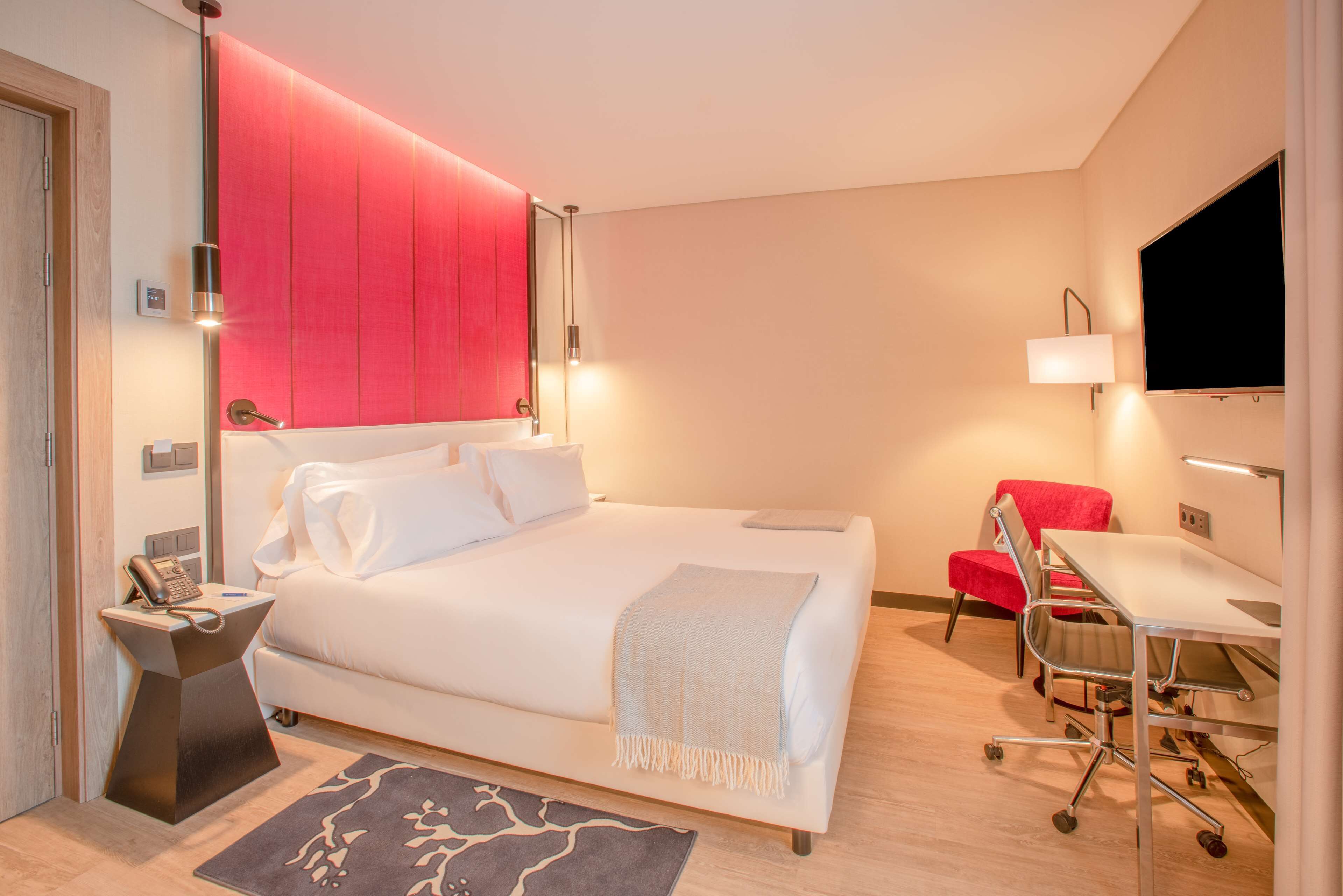 A modern hotel room with a large bed, a desk, and a TV.