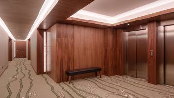 A hallway with wooden walls, a bench, and an elevator.