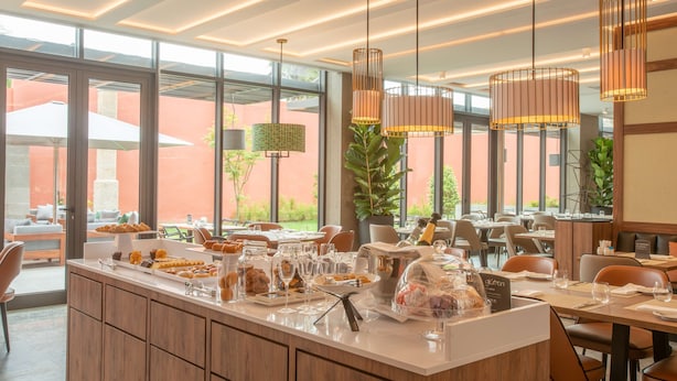 Un comedor moderno con una barra larga, diversos alimentos y lámparas colgantes.