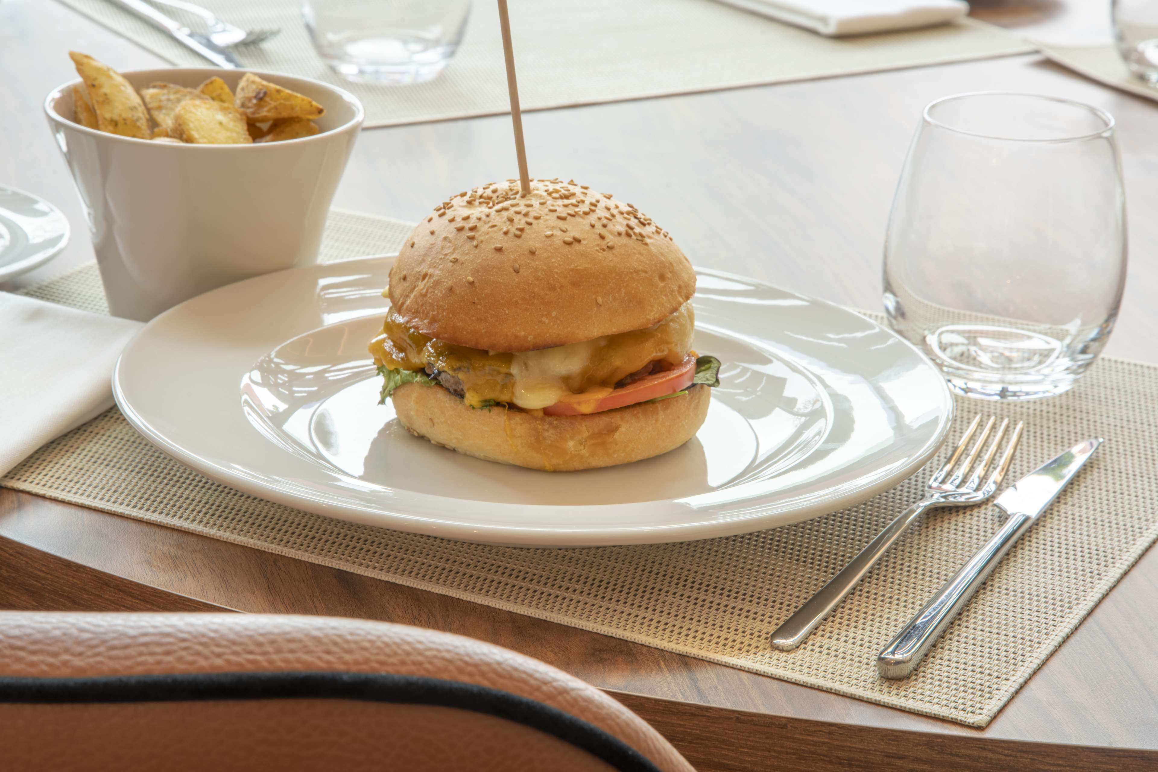 En tallerken med en burger og en skål pommes frites på et bord med en bordskåner.
