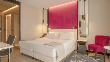 A modern hotel room with a large bed, a desk, and a chair.