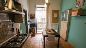 A compact kitchen with a gas stove, a dining table with chairs, and a view of the outside balcony. - Entire apartment with Cathedral view, 2 bedrooms and 2 bathrooms, fully equipped (Palermo)