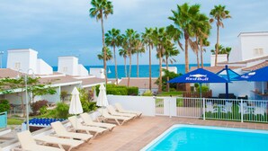 A pool area with lounge chairs, a pool, and palm trees. - Bungalows Side Shore (San Bartolome de Tirajana)