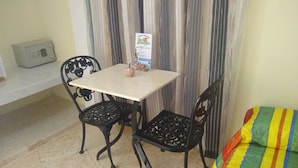A small room with a table and two chairs, a bed with a colorful blanket, and a wall-mounted heater. - Hostal Los Mangos (Santa Marta)
