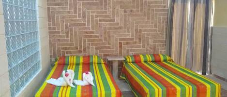 A hotel room with two beds, each with a colorful striped bedspread.