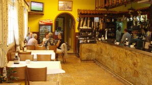 A restaurant interior with tables, chairs, a bar area, and a television screen. - Hostal Restaurante La Cepa (Carino)