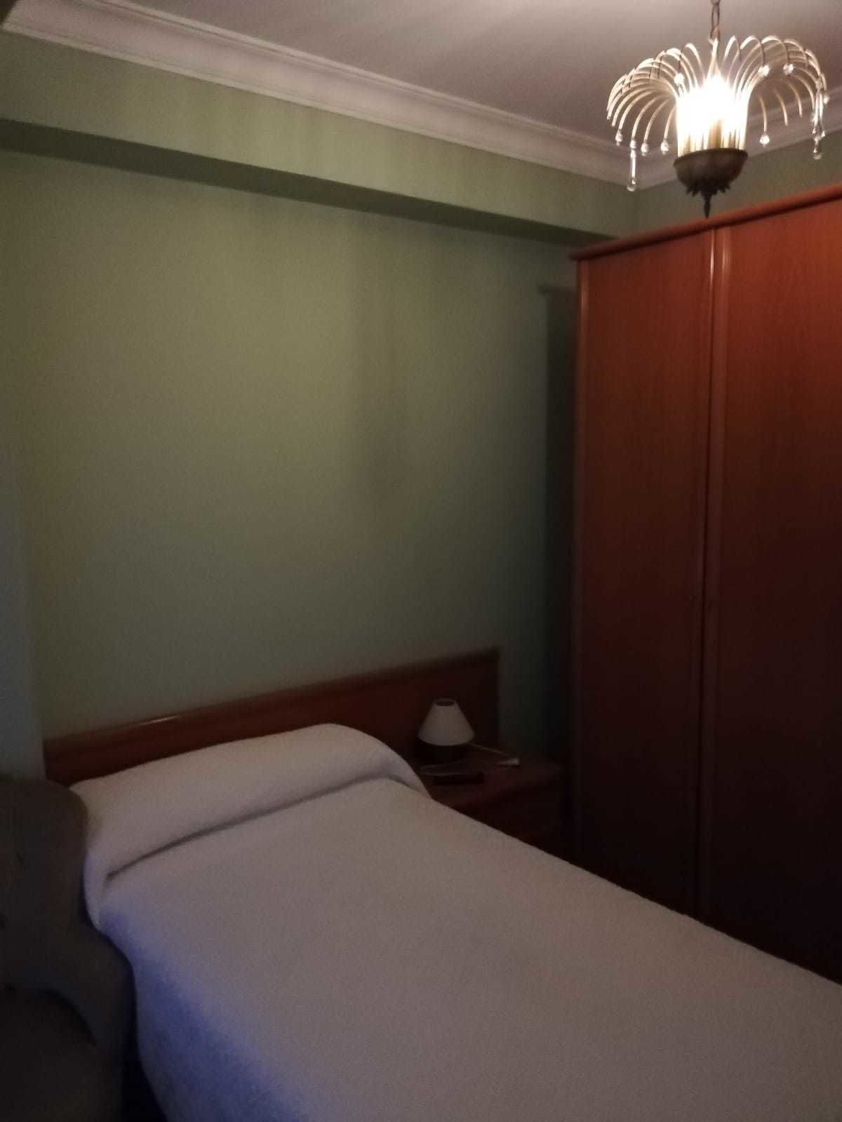 A hotel room with a bed, a nightstand, a lamp, and a wardrobe.