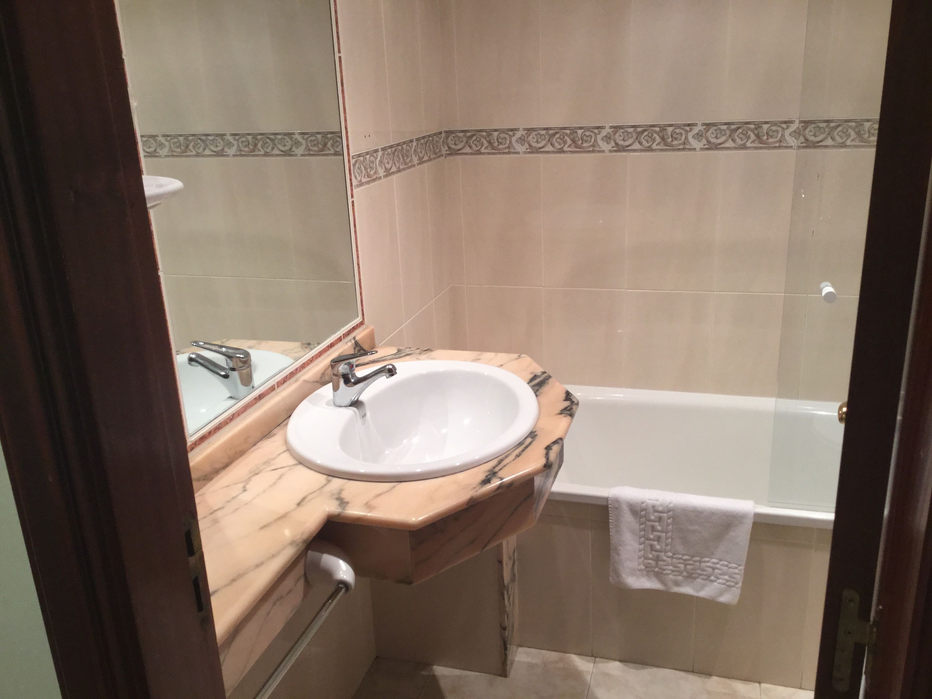A bathroom with a marble sink, a mirror, and a bathtub.