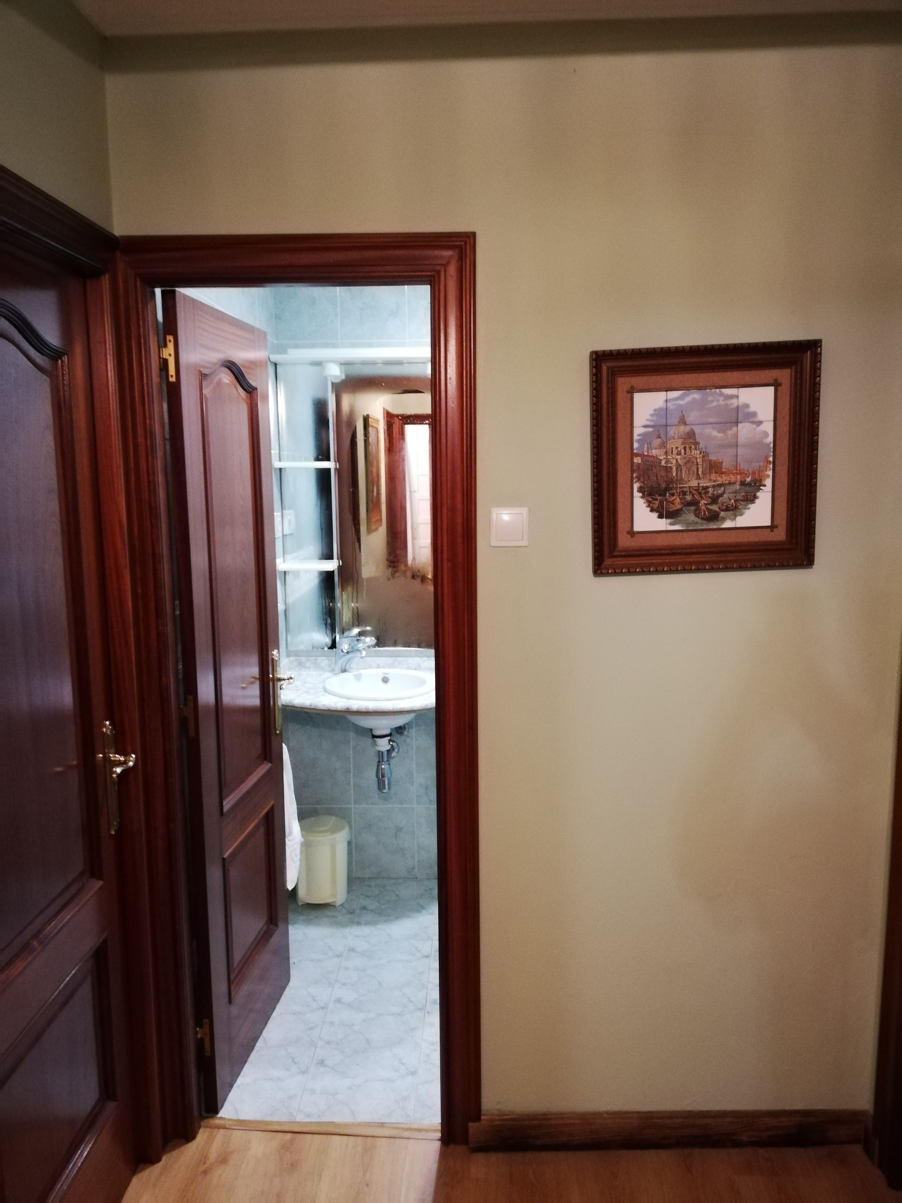 Pasillo que conduce a un baño con lavamanos y espejo.