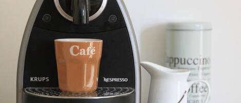 Eine Krups Nespresso Kaffeemaschine mit einer Kaffeetasse und einer weißen Kaffeekanne auf einem Tablett.