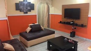 A living room with a sofa, a coffee table, and a flat-screen TV mounted on the wall. - Pent House Appartment (Lagos)