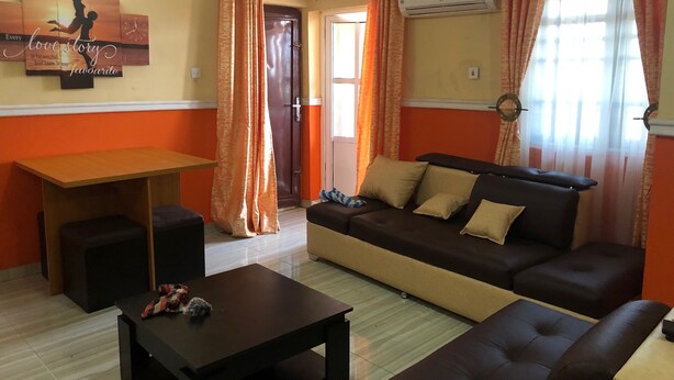 A living room with a sofa, a coffee table, a small table, and a door. - Pent House Appartment (Lagos)