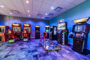 A row of arcade machines with a wooden floor and a blue wall.