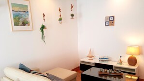 A living room with a white sofa, a coffee table, and a small bookshelf. - Enjoy Oporto Flat (Porto)