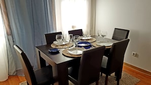 A dining table set with plates, glasses, and cutlery, surrounded by chairs. - Enjoy Oporto Flat (Porto)