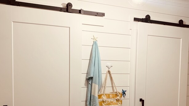 Ein Zimmer mit zwei weißen Türen, einer hängenden Leuchte und einem Holzboden.