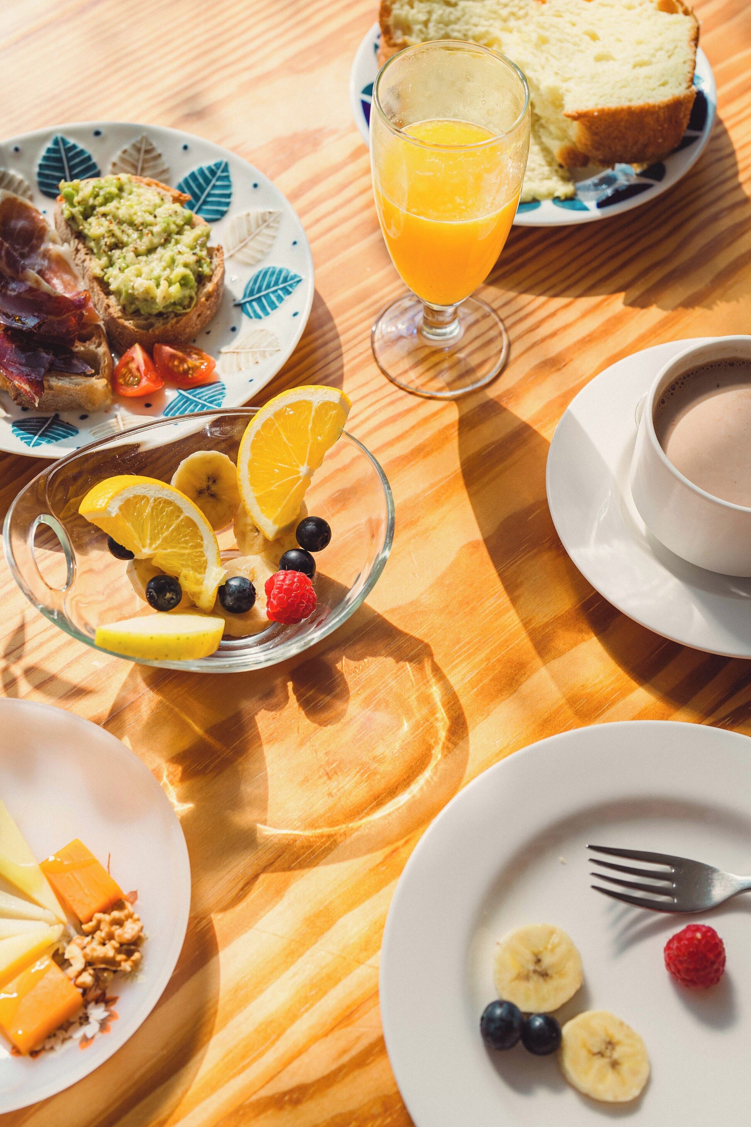 Ein Frühstückstisch mit Toast, Obst und einem Glas Orangensaft.