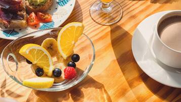 A breakfast setting with plates of toast, fruit, and a glass of orange juice.