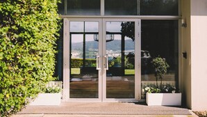 Entrada moderna de un edificio con puerta de vidrio, una planta en maceta y vistas al exterior.