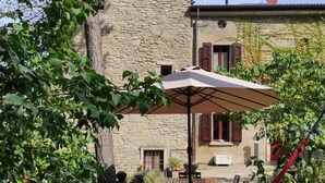 A stone building with a tiled roof, a hammock, and a table with chairs in the foreground. - Romantic tower house with swimming pool (Ravenna, Bologna, Florence) (Casola Valsenio)