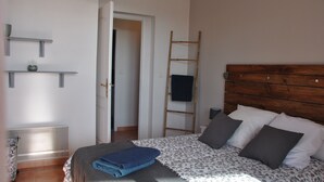 A bedroom with a bed, a wooden ladder, a white door, and a wall-mounted shelf. - Large T3 with terrace, sea view, 20 metres from the beach (NARBONNE PLAGE)
