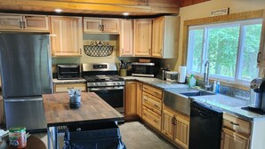 A kitchen with wooden cabinets, a stainless steel refrigerator, a microwave, a stove, and a dishwasher. - Waterfront Lakehouse (Stetson)